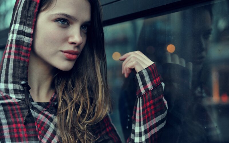 woman in plaid hoodie by window
