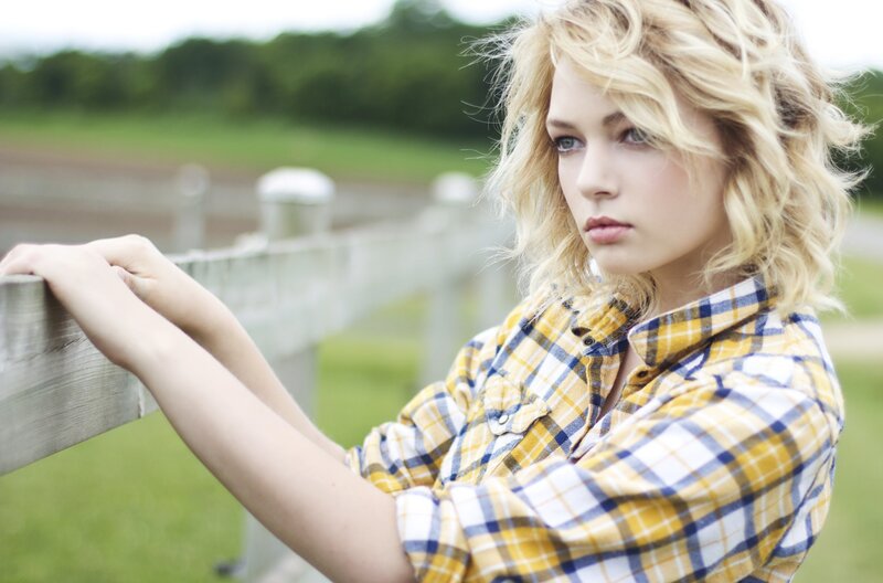 woman in plaid shirt by fence