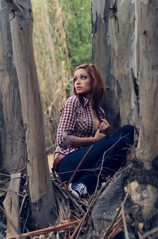 woman in plaid shirt sitting among trees