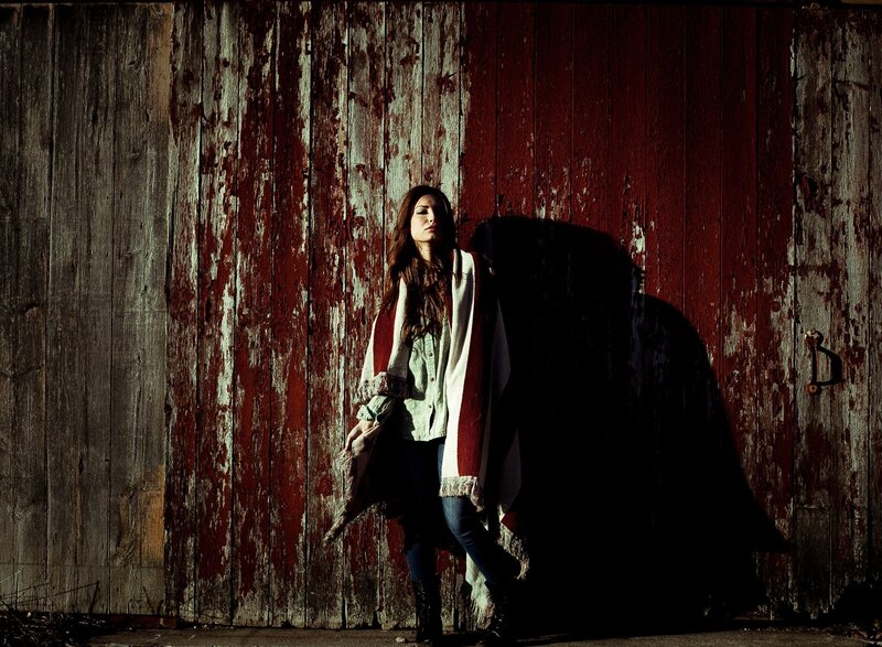 woman in poncho against red barn