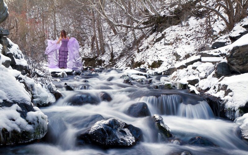 Woman in purple dress by snowy stream