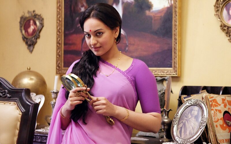woman in purple sari holding magnifying glass