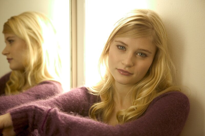woman in purple sweater by window