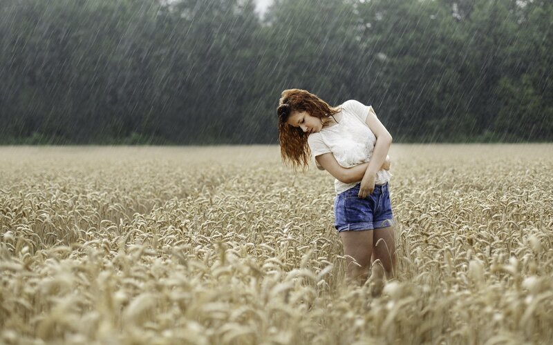 woman in rain-soaked wheat field