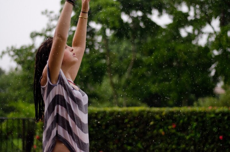 woman in rain with arms raised