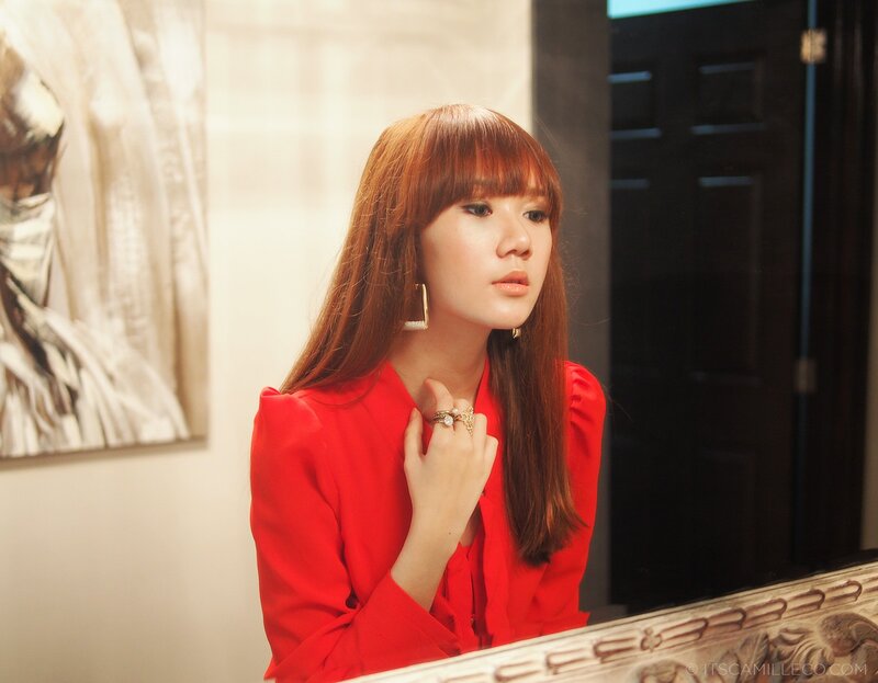 woman in red blouse looking at mirror