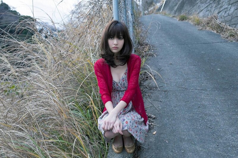 Woman in red cardigan sitting on path