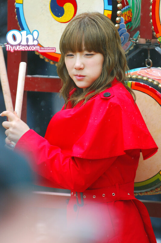 woman in red coat holding drumsticks
