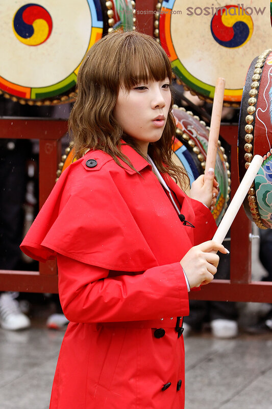 woman in red coat playing drums