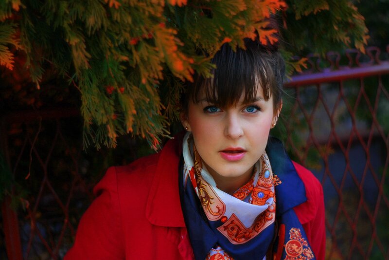 woman in red coat under foliage