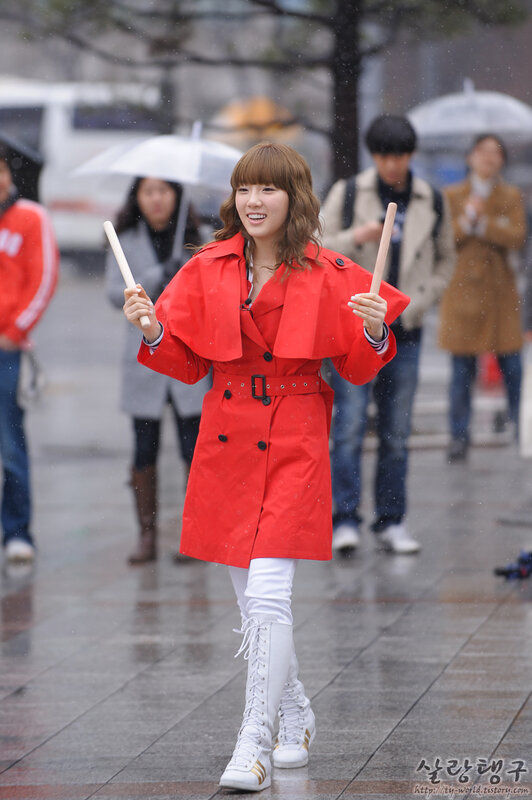 woman in red coat with drumsticks