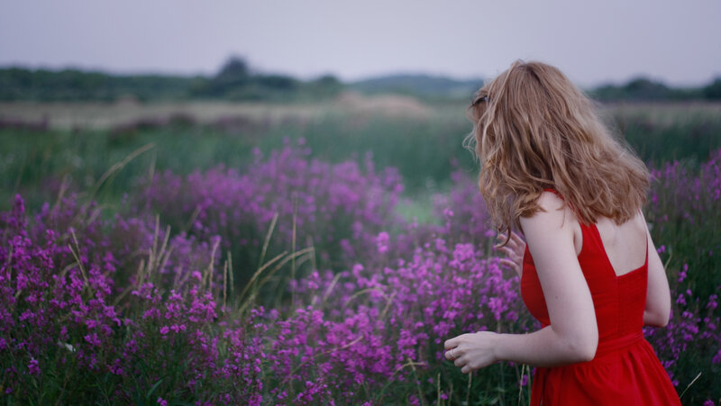 Woman in red dress among purple flowers