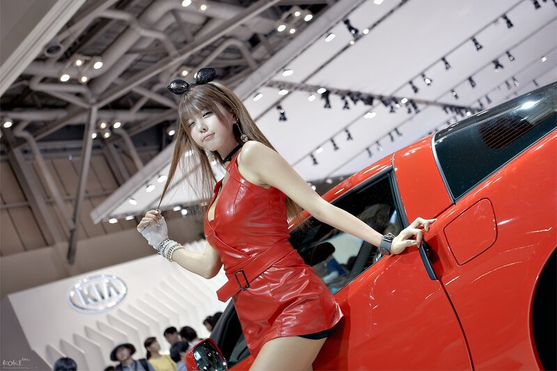 Woman in red dress at car show
