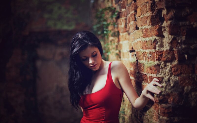 woman in red dress by brick wall