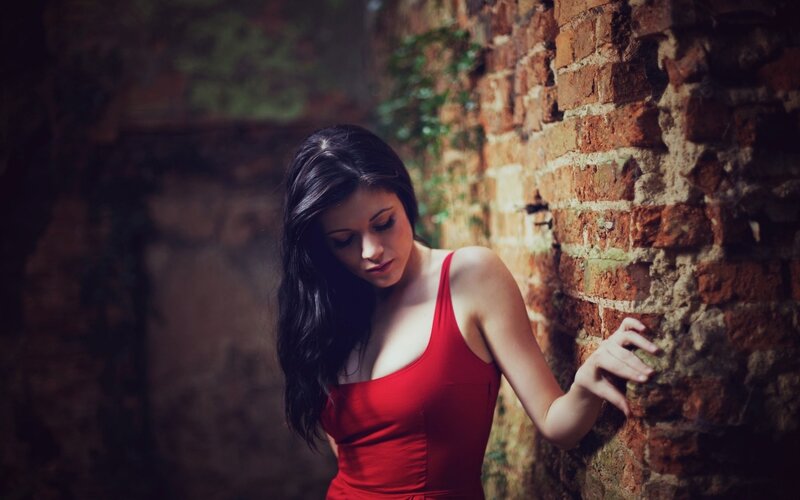 woman in red dress by brick wall