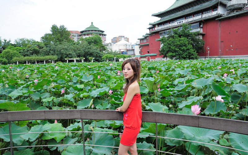 Woman in red dress by lotus pond
