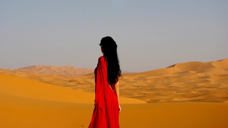 woman in red dress on desert dunes