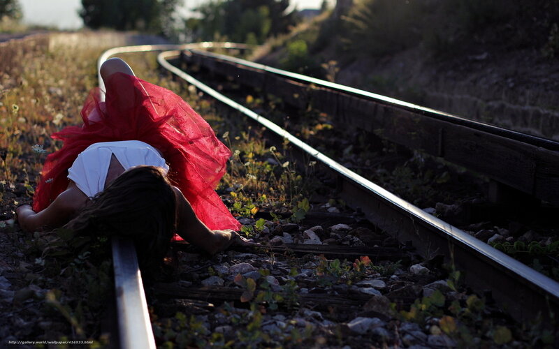 Woman in red dress on train tracks