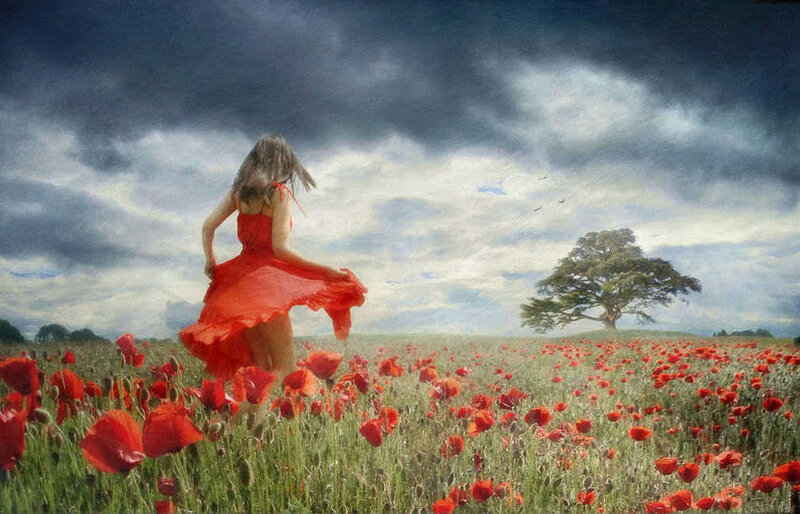 Woman in red dress running through poppy field