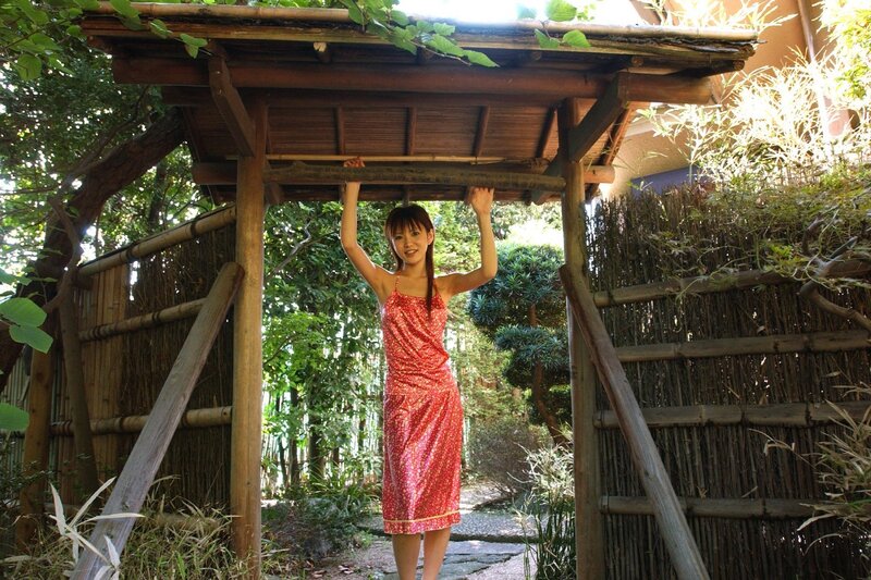 Woman in red dress under bamboo gate