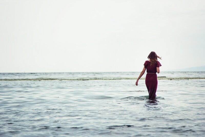 woman in red dress walking in water