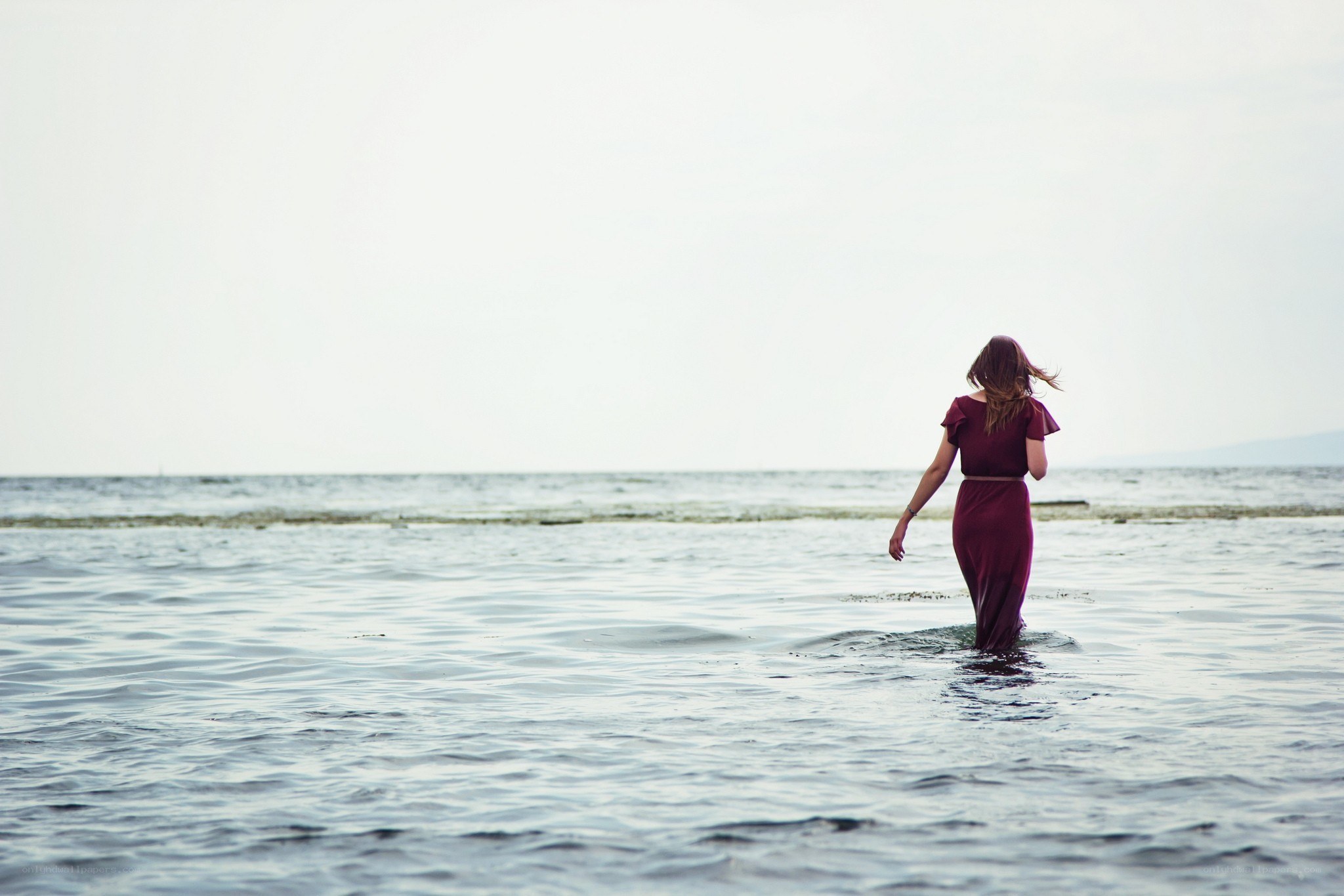 woman in red dress walking in water