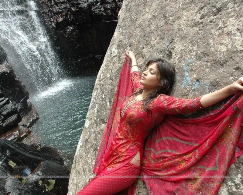 Woman in red sari by waterfall