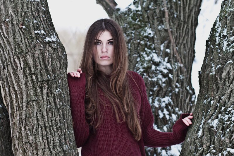 woman in red sweater between trees