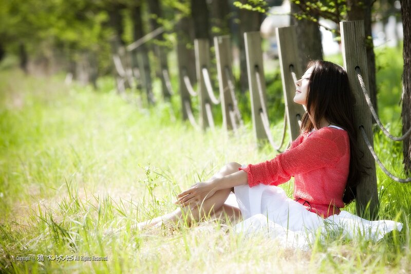Woman in red sweater sitting in grass