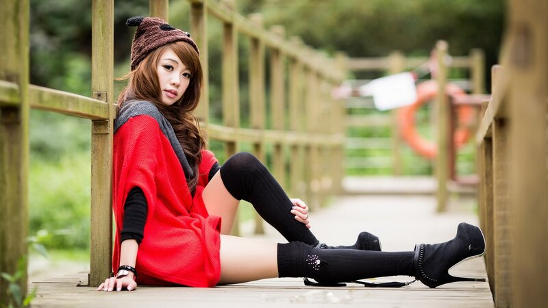 Woman in red sweater sitting on bridge