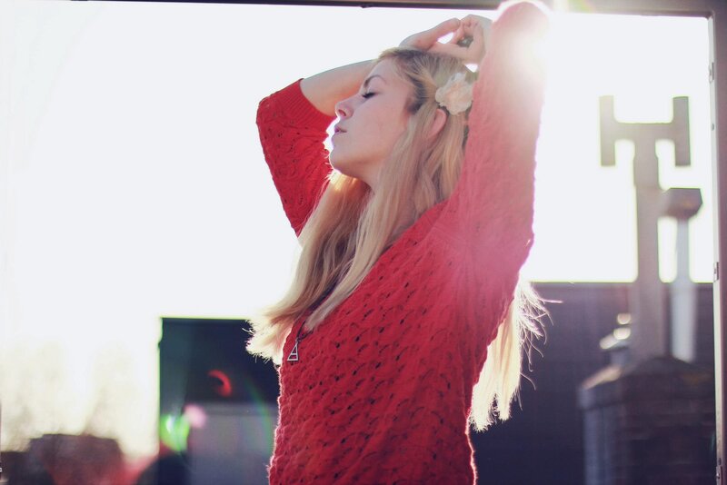 woman in red sweater with sun flare