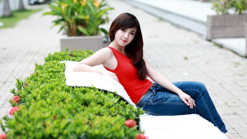 Woman in red top sitting on hedge