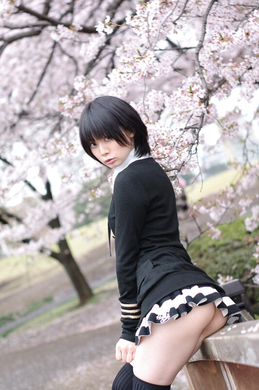 Woman in school uniform under cherry blossoms