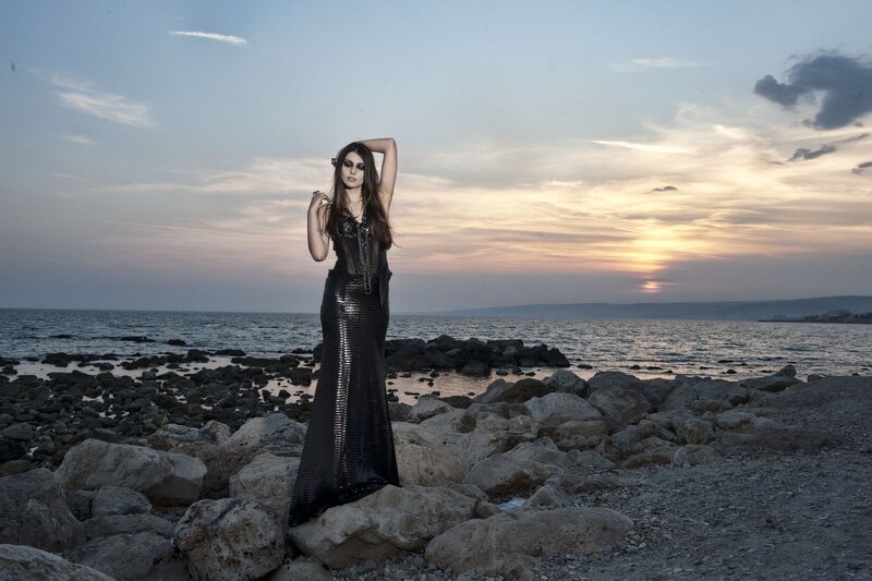 Woman in sequined dress on rocky shore