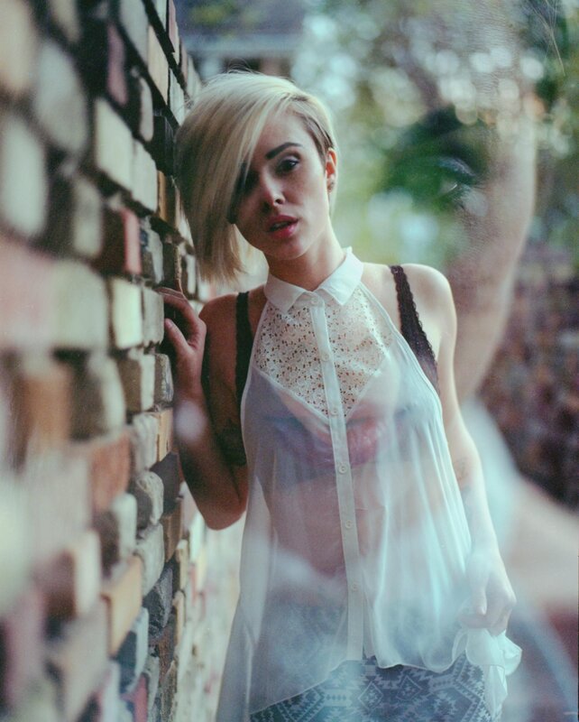 woman in sheer top by brick wall