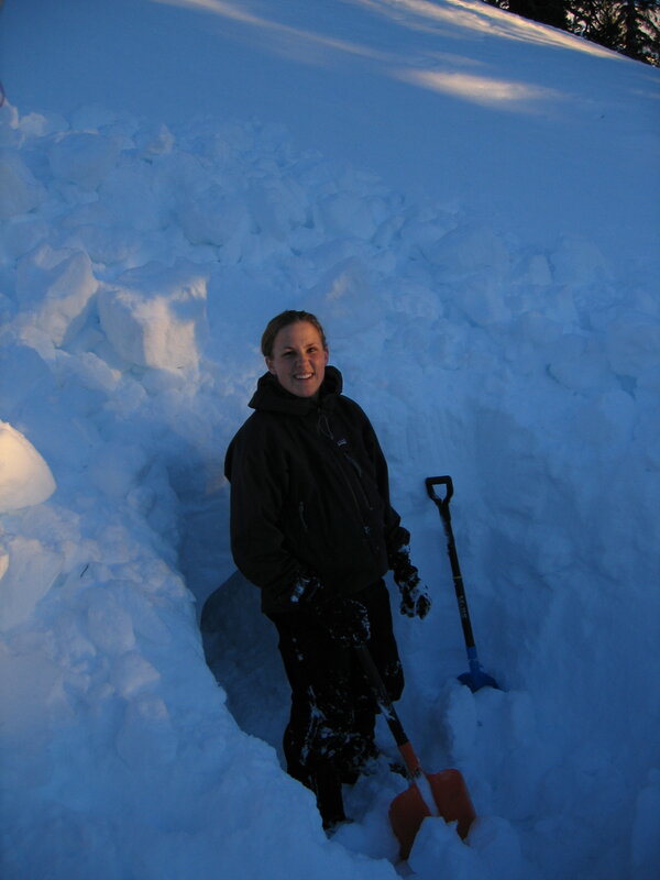 Woman in snowy trench with shovel