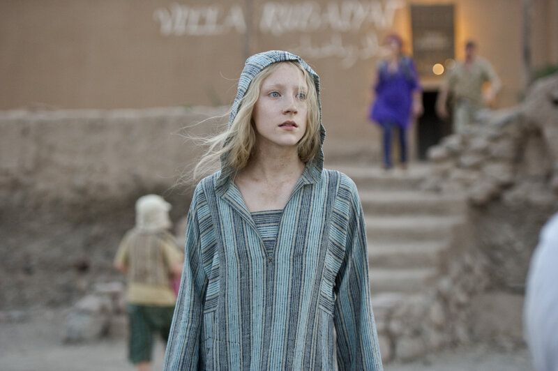 woman in striped robe stands outside