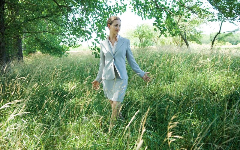 Woman in suit walking through field