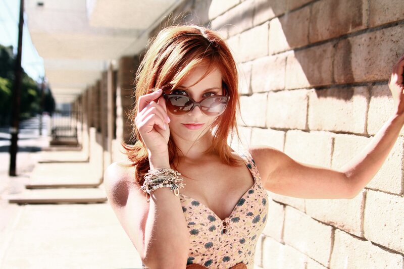 woman in sunglasses by brick wall