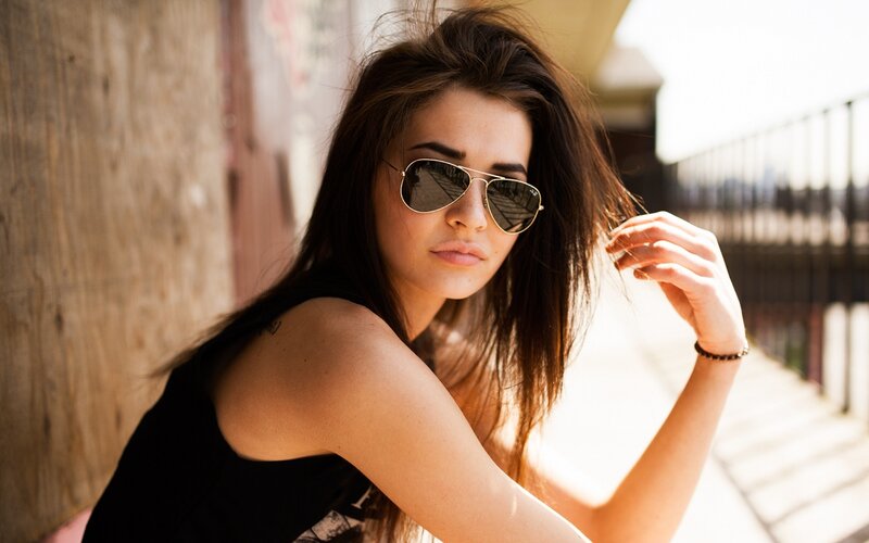woman in sunglasses leaning against wall