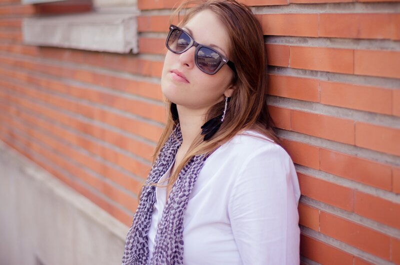 woman in sunglasses leaning on brick wall