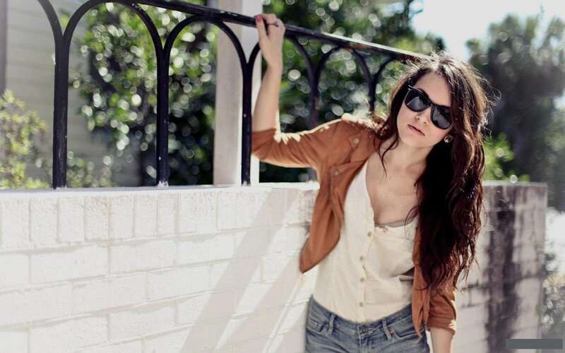woman in sunglasses leaning on wall