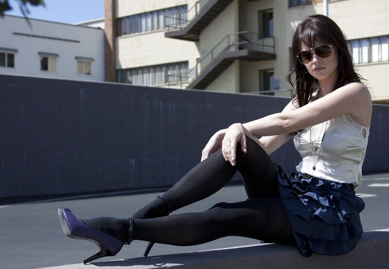 Woman in sunglasses sitting on ledge