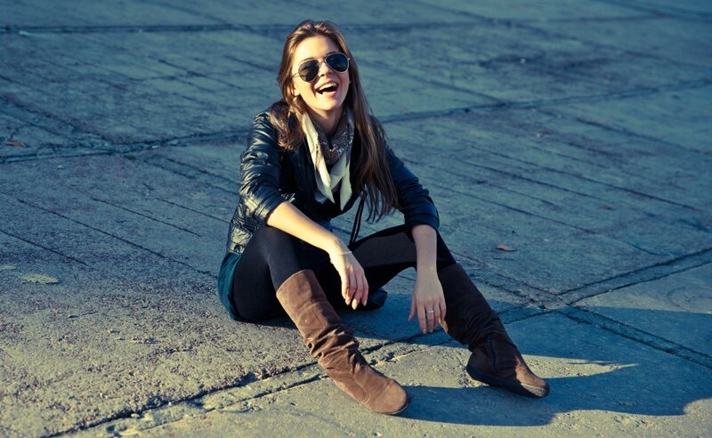 woman in sunglasses sitting on pavement