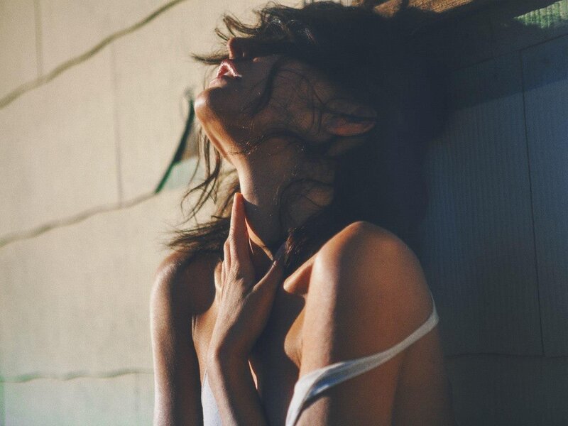 woman in sunlight with hand on neck