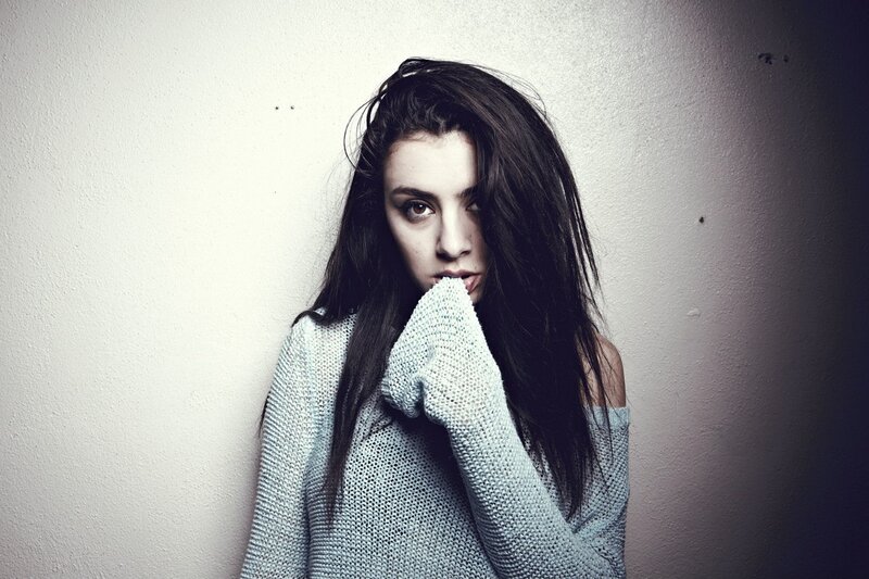 woman in sweater covering mouth
