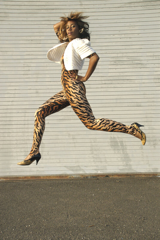 woman in tiger-print jumpsuit jumping