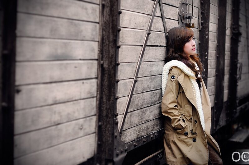 woman in trench coat by train