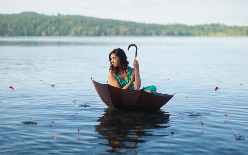 Woman in umbrella boat on lake