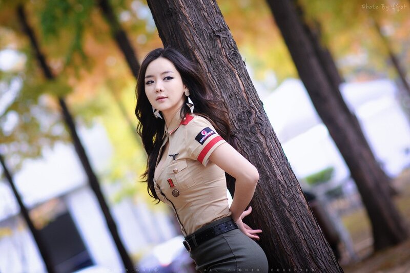 Woman in uniform leaning on tree